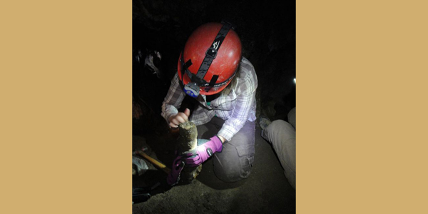 kneeling person studying cave rock