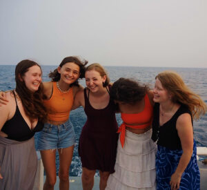 A group of students laughing in front of the ocean.