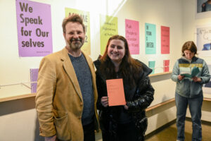 Ella Jasie, a sophomore majoring in culture, advocacy, and leadership, posing with artist Tom Williams.